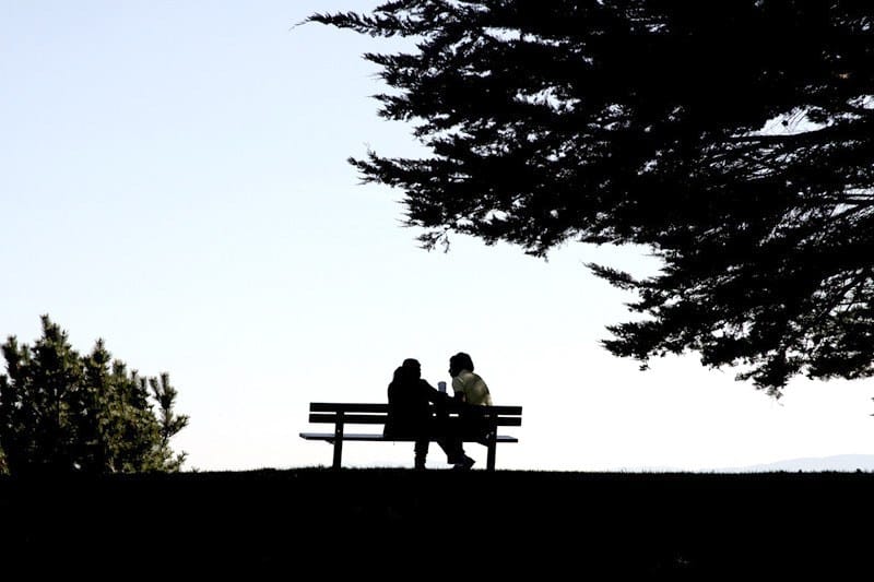 Silhouette of a couple sitting on a bench