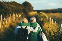 Back view of two friends walking through a field