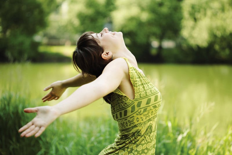 Happy girl on the field with arms outstretched