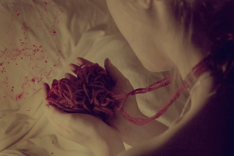 Girl looking at her hands and reminiscing, in pain