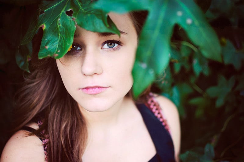 Girl peering from under leaves