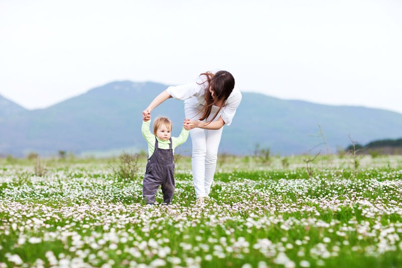 Mother teaching her child to walk on the field
