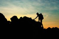 Silhouette of man climbing mountain